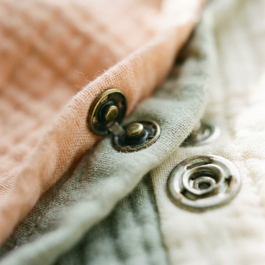 Close up of high-quality snap buttons on a muslin onesie